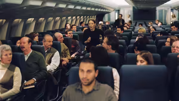 Kyle (Jodie Foster) stands in the airplane aisle addressing the passengers
