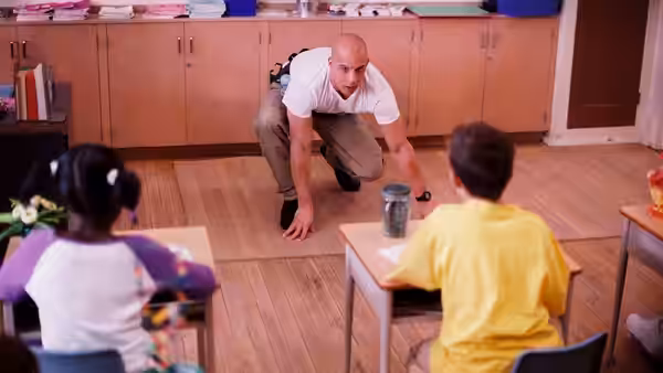 Shane Wolfe (Vin Diesel) crouches between two children seated at classroom desks