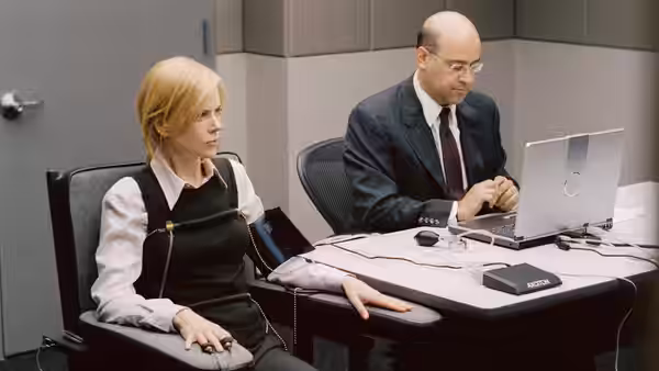 Silvia Broome (Nicole Kidman) sits beside a colleague at a computer in an office