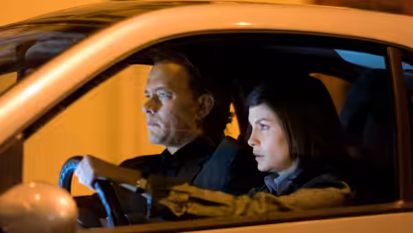 Robert Langdon (Tom Hanks) drives a car with Sophie Neveu (Audrey Tautou) beside him