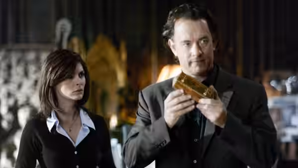Robert Langdon (Tom Hanks) examines a golden object beside Sophie Neveu (Audrey Tautou) in a museum