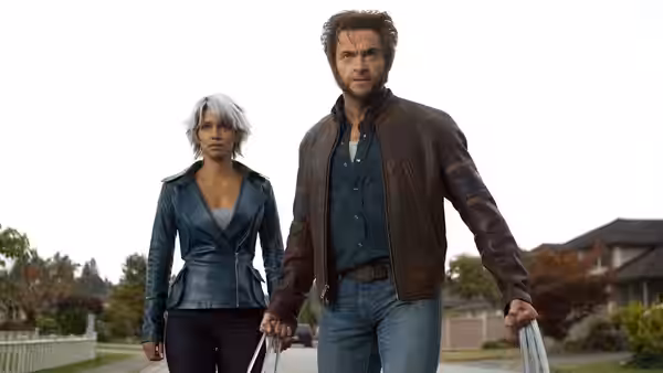 Storm (Halle Berry) walks beside Wolverine (Hugh Jackman), who extends his claws in a suburban street
