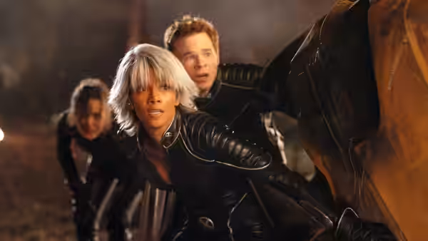 Storm (Halle Berry) and a young man crouch behind cover amid rubble