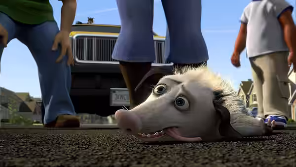 A possum lies tongue-out on the pavement beneath people standing beside a truck