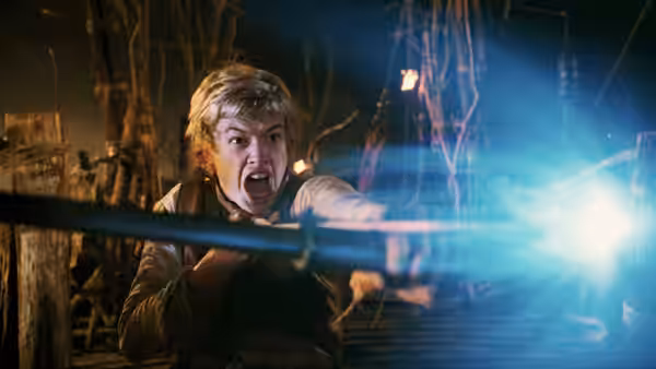 Eragon (Ed Speleers) thrusts his sword forward as blue magic flares in the woods