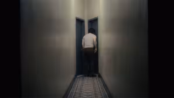 A man in a white shirt standing before blue doors in a hallway