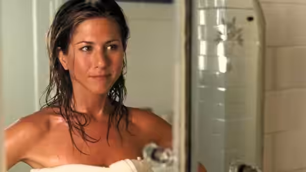 Brooke (Jennifer Aniston), wrapped in a towel, stands in the bathroom