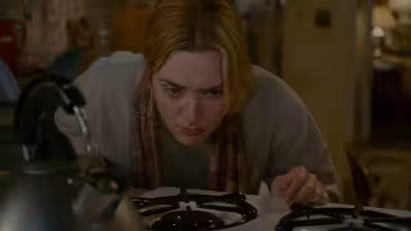 Iris (Kate Winslet) leans over a gas stove in the kitchen