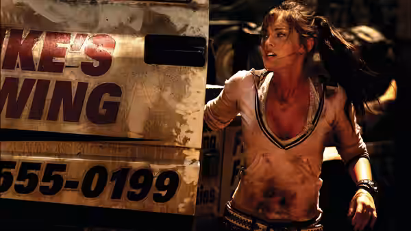 Mikaela Banes (Megan Fox) runs past a battered truck amid smoke and debris