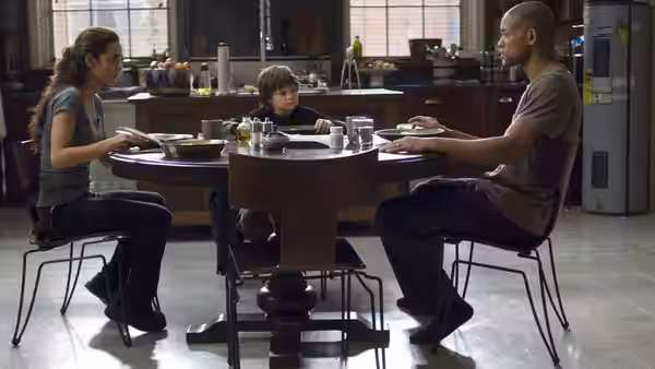 Robert Neville (Will Smith), Anna (Alice Braga) and Ethan (Charlie Tahan) sit around a dining table