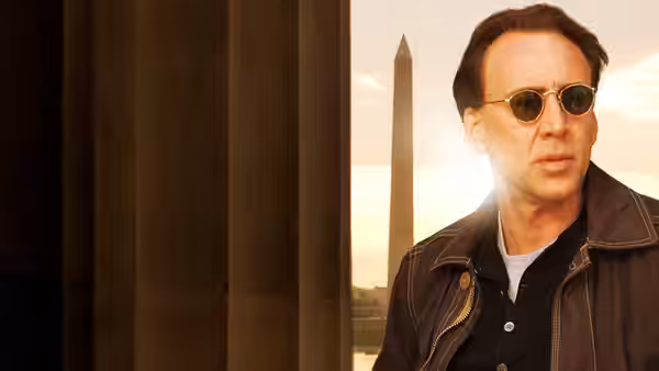 Ben Gates (Nicolas Cage) wears round sunglasses beside a window overlooking the Washington Monument