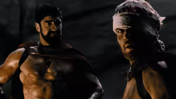 Leonidas (Gerard Butler) stands beside a bandaged Spartan soldier in the dark