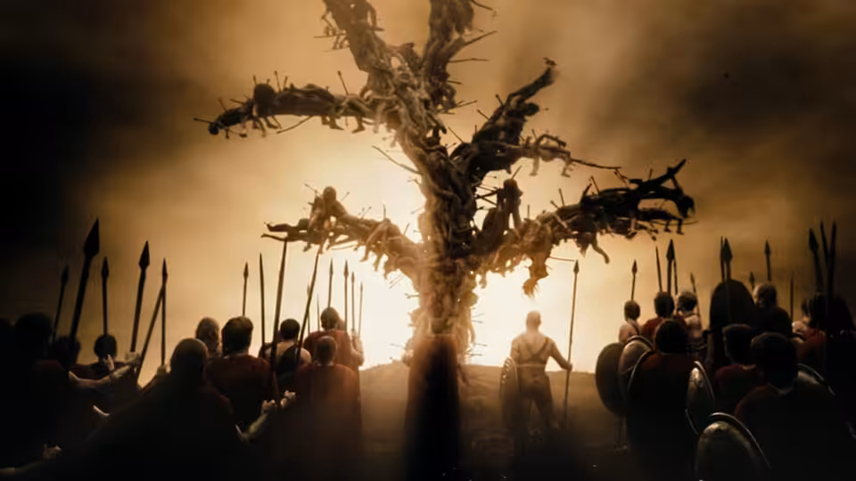 Spartan soldiers gather beneath a tree bearing bodies impaled on its branches