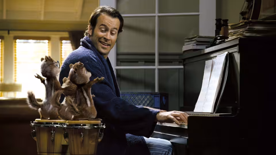 Dave (Jason Lee) plays piano as the chipmunks dance on bongos beside him