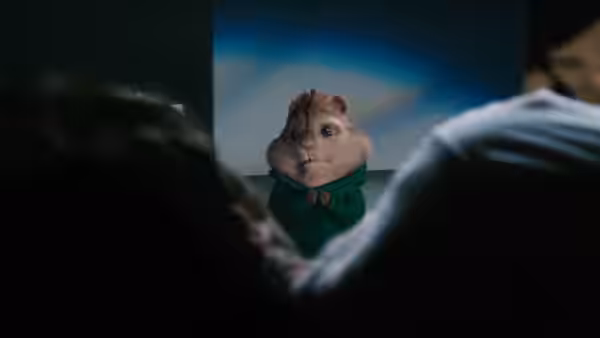 Theodore stands under a spotlight, facing an audience in the dark