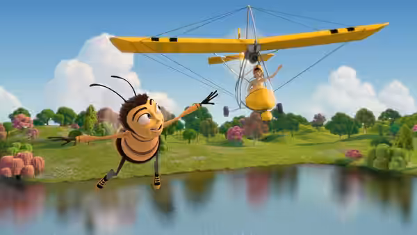 Barry waves beside a person suspended beneath a hang glider over a lake