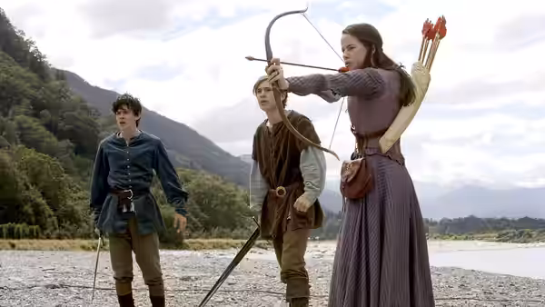 Susan Pevensie (Anna Popplewell) aims her bow while Peter and Edmund watch by the river