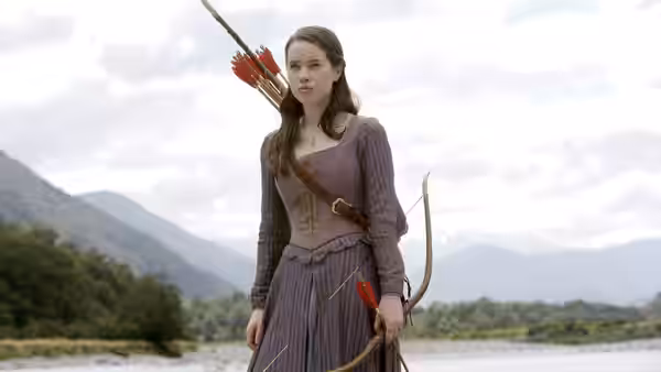 Susan Pevensie (Anna Popplewell) stands with her bow and arrows on a mountain riverbank