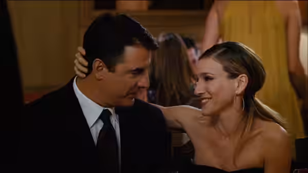 Mr. Big (Chris Noth) sits beside Carrie Bradshaw (Sarah Jessica Parker) at a formal gathering