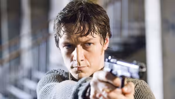 Wesley Gibson (James McAvoy) aims a pistol inside a bright industrial building