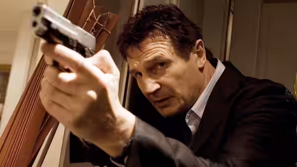 Bryan Mills (Liam Neeson) aims a pistol from beside a doorway