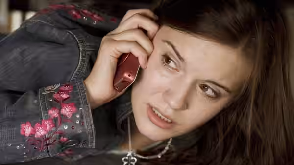Kim Mills (Maggie Grace) speaks on a phone while lying down