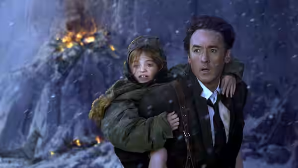 Jackson Curtis (John Cusack) carries Noah through a snowstorm as flames burn behind them