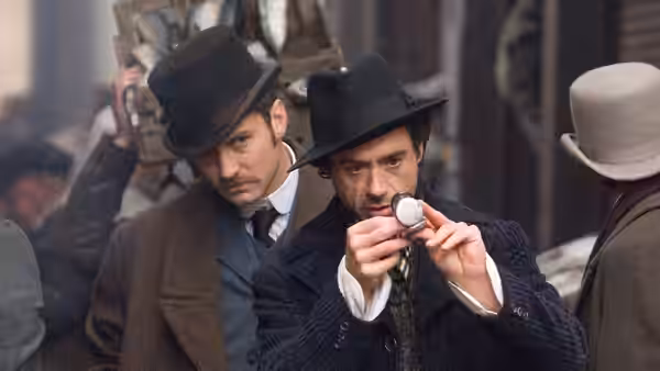 Sherlock Holmes (Robert Downey Jr.) examines a pocket watch as Dr. Watson (Jude Law) watches