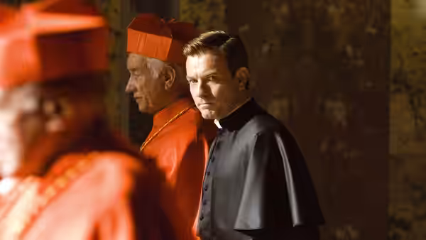 Camerlengo Patrick McKenna (Ewan McGregor) stands beside a cardinal in red robes