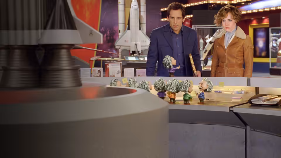 Larry Daley and Amelia Earhart examine miniature figures beside a space shuttle exhibit