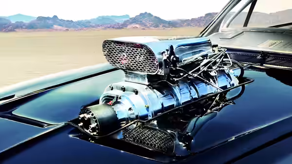 A supercharged engine rises from the hood of a car in the desert