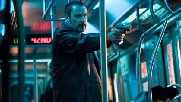 Ryder (John Travolta) aims a handgun inside a subway car