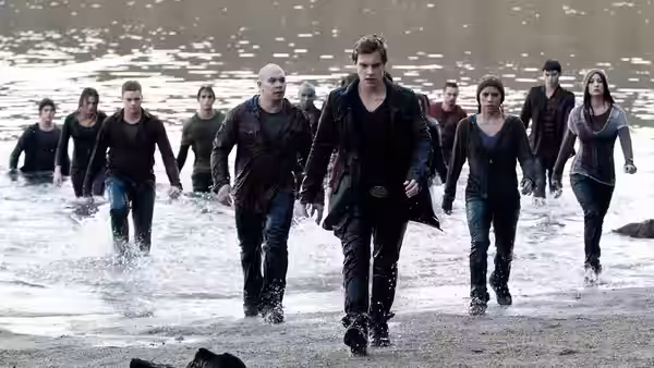 A group of young vampires wades through shallow water toward shore