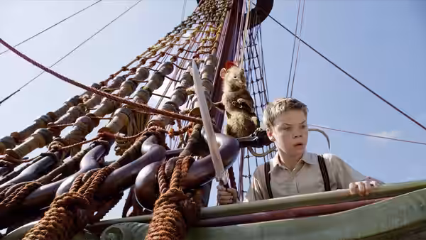 Eustace Scrubb (Will Poulter) grips the ship’s railing as Reepicheep climbs the rigging behind him