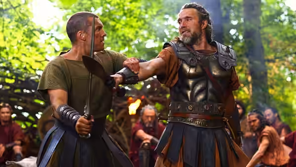 Perseus (Sam Worthington) holds back a warrior's sword during a forest confrontation