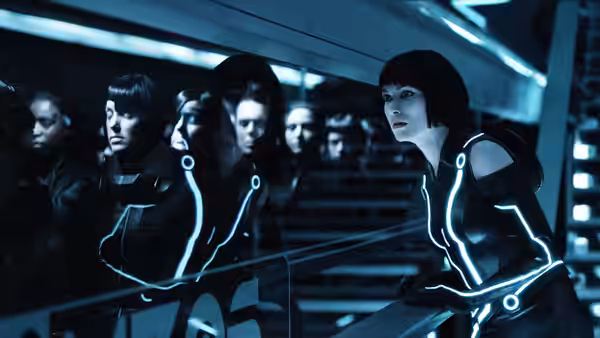 Quorra (Olivia Wilde) leans over a railing beside rows of people