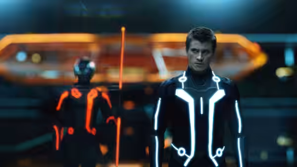 Sam Flynn (Garrett Hedlund) stands before a red-lit figure in the Grid
