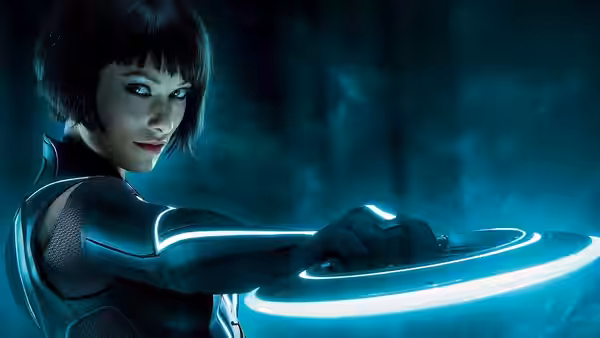 Quorra (Olivia Wilde) holds a glowing identity disc against a dark backdrop