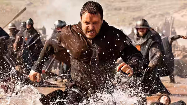 Robin Longstride (Russell Crowe) charges through water as armored soldiers fight behind him