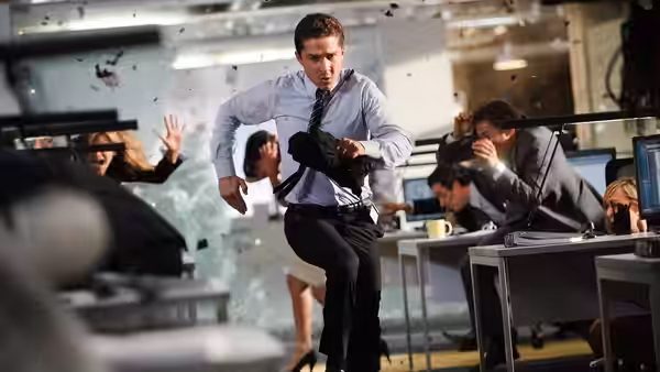 Sam Witwicky (Shia LaBeouf) runs through an office as people duck from flying debris