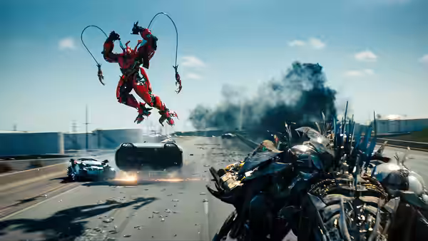 A red robot leaps over a highway as vehicles pursue a spiked Decepticon