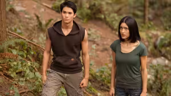 A young man and woman walk through a wooded trail