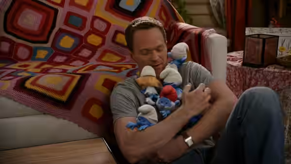 Patrick Winslow (Neil Patrick Harris) cuddles a bundle of Smurfs on a sofa