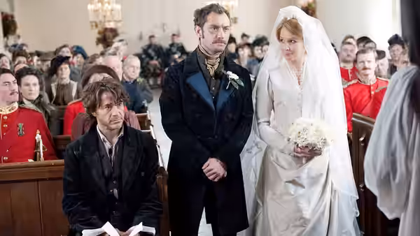 Dr. John Watson (Jude Law) sits beside Sherlock Holmes (Robert Downey Jr.) at Watson's wedding