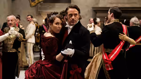 Sherlock Holmes (Robert Downey Jr.) dances with a woman in a red gown at a formal ball