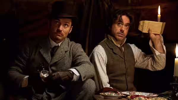 Dr. John Watson (Jude Law) examines a bottle as Sherlock Holmes (Robert Downey Jr.) holds up a box