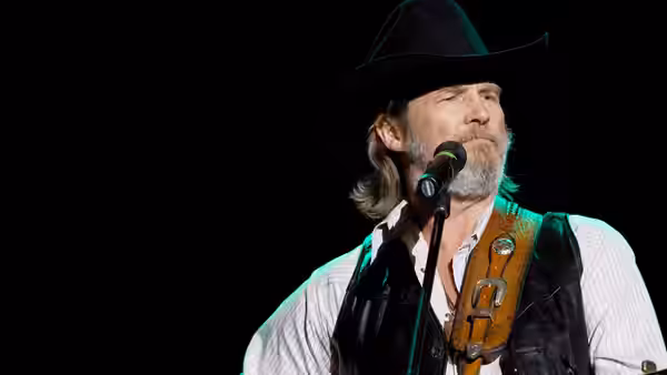 Bad Blake (Jeff Bridges) sings at a microphone onstage in a black cowboy hat