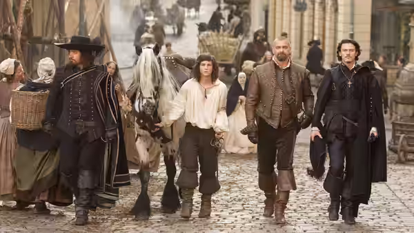 D’Artagnan walks through a crowded street with three musketeers and a horse