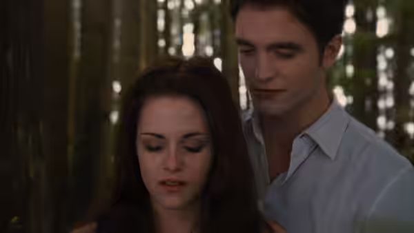 Bella Swan (Kristen Stewart) stands with Edward Cullen (Robert Pattinson) in the forest