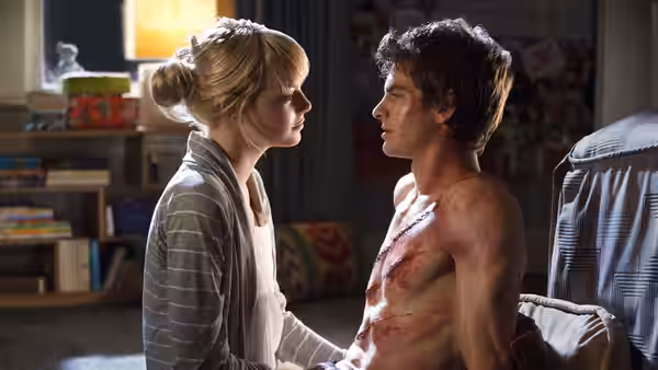 Gwen Stacy (Emma Stone) tends to Peter Parker (Andrew Garfield), seated shirtless and injured